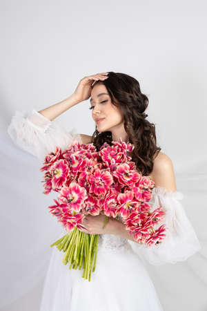 Young woman with pink tulips in hands, white dressの写真素材
