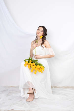 Sexy woman with flowers tulips in hands on a white backgroundの写真素材