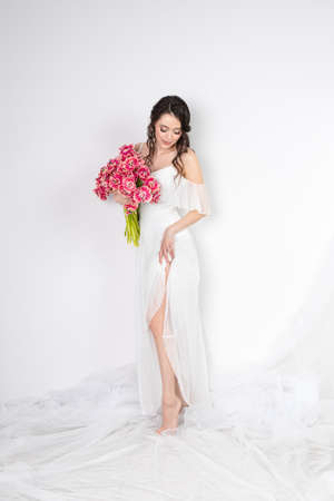 Sexy woman with flowers pink tulips in hands on a light backgroundの写真素材