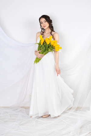 Sexy woman with flowers tulips in hands on a white backgroundの写真素材
