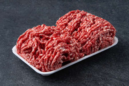 Fresh raw minced beef on backing paper over dark gray cement background