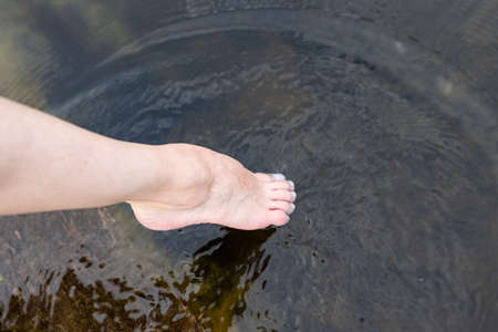Woman feet slow life and relax on river bark with sunsetの写真素材