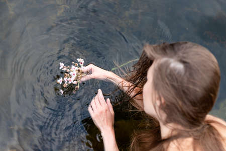 The female hand that touches the blue water. The lake is clean. With a drop of water on the waterの写真素材