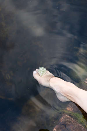 Woman feet slow life and relax on river bark with sunsetの写真素材
