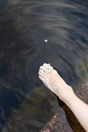 Woman feet slow life and relax on river bark with sunsetの写真素材