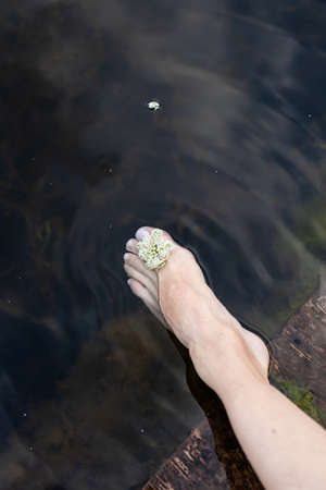 Woman feet slow life and relax on river bark with sunsetの写真素材