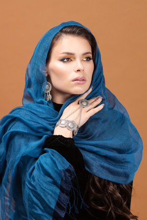 Attractive woman's face in scarf. Close up portrait of pretty female model on amber backgroundの写真素材