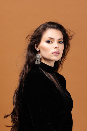 Smiling, dreamful young woman's portrait on amber studio background. Beautiful female model in casual style.の写真素材