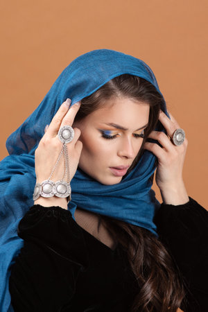Attractive woman's face in scarf. Close up portrait of pretty female model on amber backgroundの写真素材