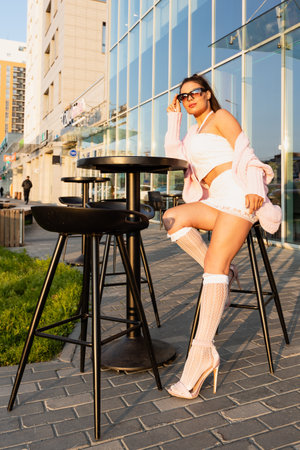 Young woman with wavy hair posing outdoors, in a city street, wearing sunglassesの写真素材