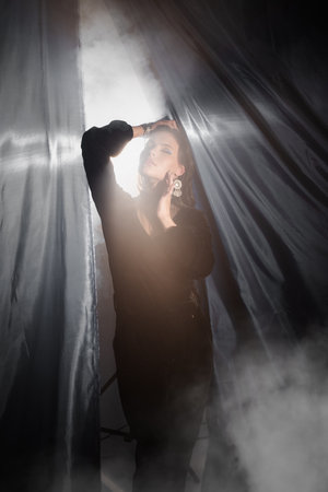 Elegant girl in black posing near the curtains. close-up.の写真素材