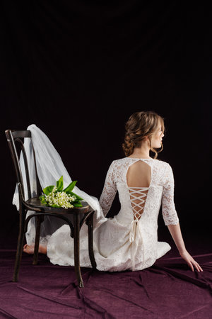 cheerful bride in white wedding dress holding flowersの写真素材