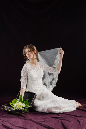 cheerful bride in white wedding dress holding flowersの写真素材