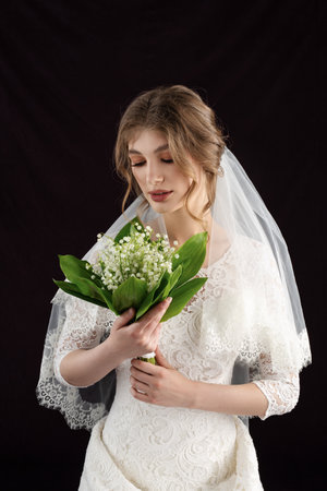 Portrait of a young woman in a wedding image. Wedding hairstyle and bright makeup. A elegant white flower in her handsの写真素材