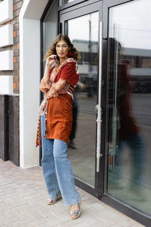 lifestyle fashion portrait of a young stylish hipster woman walking down the street wearing trendy outfitの写真素材