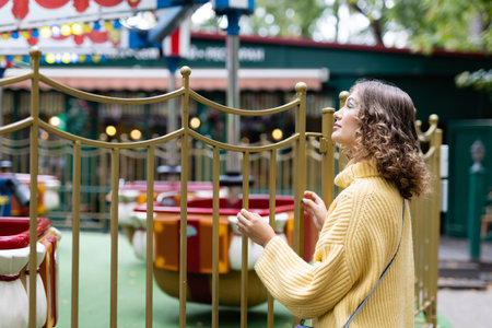 Woman in an amusement park look on a carousel and smiles with happiness, the concept of weekendsの写真素材