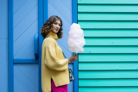 Young brunette eating a cotton candy outdoorsの写真素材