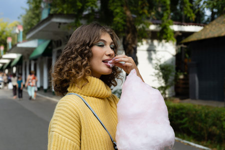 Young brunette eating a cotton candy outdoorsの写真素材