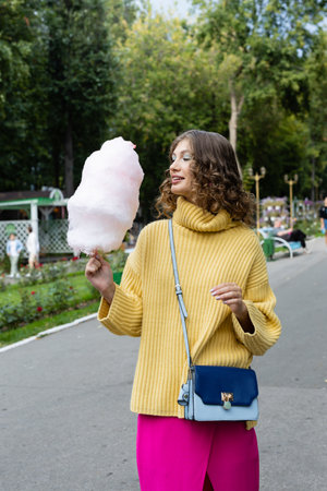 Young brunette eating a cotton candy outdoorsの写真素材