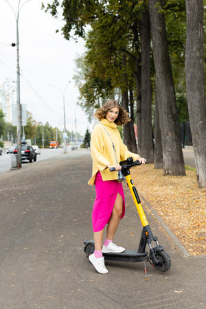 girl standing with electric scooter on a street. Riding e-scooter in summer city