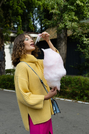 Young brunette eating a cotton candy outdoorsの写真素材