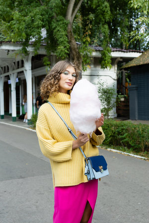 Young brunette eating a cotton candy outdoorsの写真素材