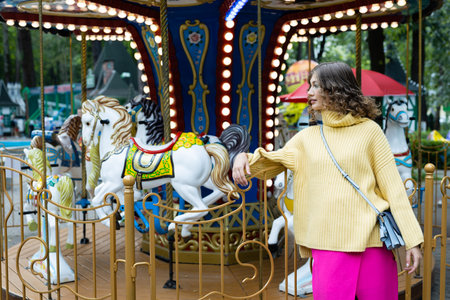 Portrait of a young happy woman on the background of a carousel in an amusement parkの写真素材