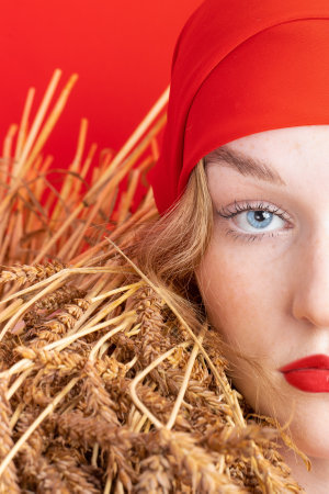 beauty young girl with blue eyes pure skin and wheat on smooth red backgroundの写真素材