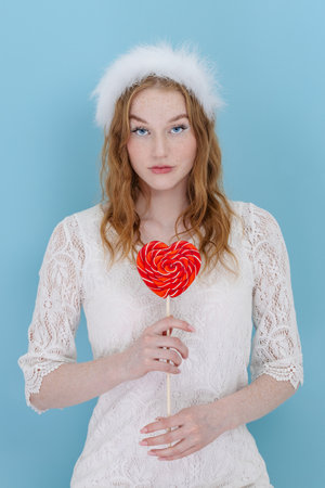 Portrait of romantic classy trend girl dream perfect 14-february dating hold heart shape lolipop over bright blue color backgroundの写真素材