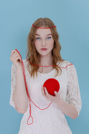 Girl hold a red thread knot. portrait on blueの写真素材