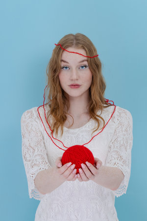 Girl hold a red thread knot. portrait on blueの写真素材