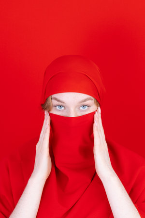 Young asian muslim woman with beautiful eyes covering her face with scarf isolated on white backgroundの写真素材