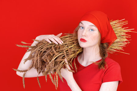 beauty young girl with blue eyes pure skin and wheat on smooth red backgroundの写真素材