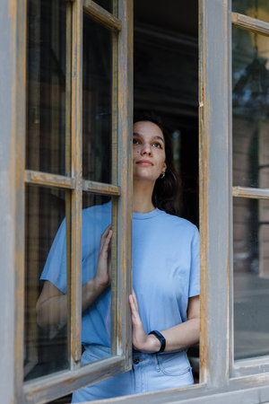 woman looking outside window with uncertainty. Thoughtful woman looking away through the window while thinking about her futureの写真素材