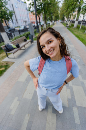 stylish positive middle aged female in jeans and sneakers strolling along city streetの写真素材