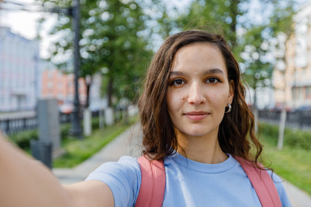 young girl takes a selfie, view from the camera on streetの写真素材