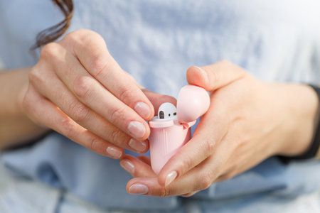 Close up of a woman hands taking off earbuds from case walking in the streetの写真素材