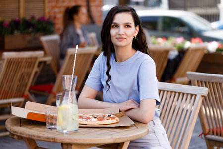Woman eating tasty pizza outdoor in street cafe. Fast food takeaway in sunny dayの写真素材
