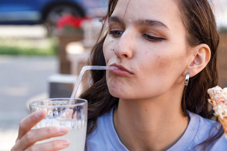 young, black hair woman drink lemonade outdoor cafeの写真素材