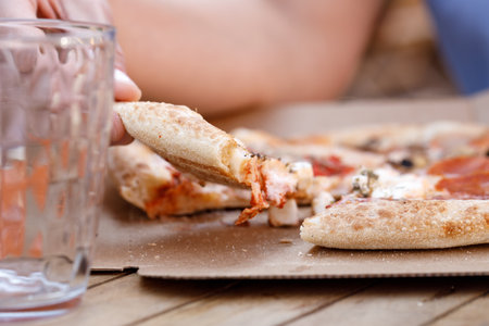 Woman eating tasty pizza outdoor in street cafe. Fast food takeaway in sunny dayの写真素材