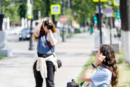 Interested female photographer working on the street. Outdoor photo of woman photographer with cameraの写真素材