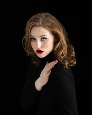 Studio portrait of beautiful redhead woman with freckles wearing black dress on dark backgroundの写真素材