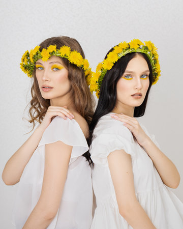 two Young girls with wreaths from dandelionsの写真素材