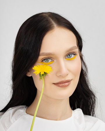 Happy smiling young woman holding yellow dandelion flowerの写真素材