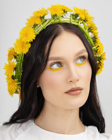 Closeup portrait Young woman in wreath from yellow dandelions.の写真素材