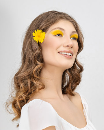 Pretty woman in white dress holding dandelion flowerの写真素材