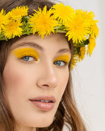 Closeup portrait Young woman in wreath from yellow dandelions.の写真素材