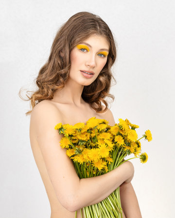 Pretty woman in white dress holding dandelion flowerの写真素材