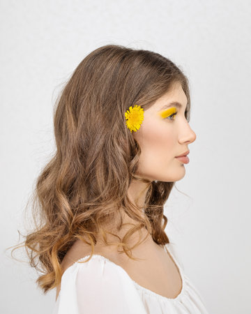 Happy smiling young woman holding yellow dandelion flowerの写真素材