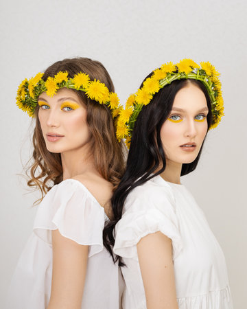 two Young girls with wreaths from dandelionsの写真素材